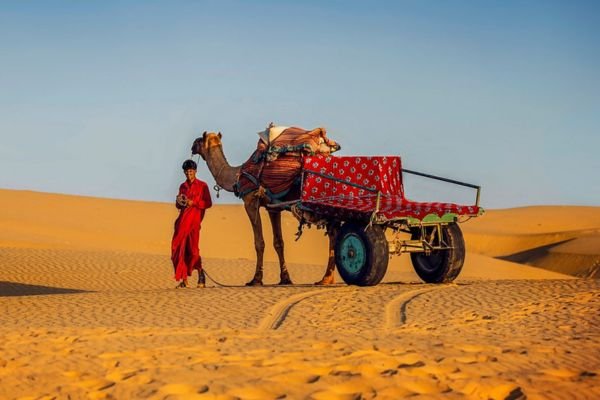 Tourists riding camels across Sam Sand Dunes at sunset